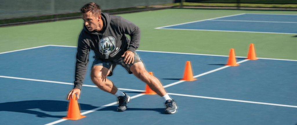 Player performing pickleball agility drills with a zigzag sprint pattern across court cones.