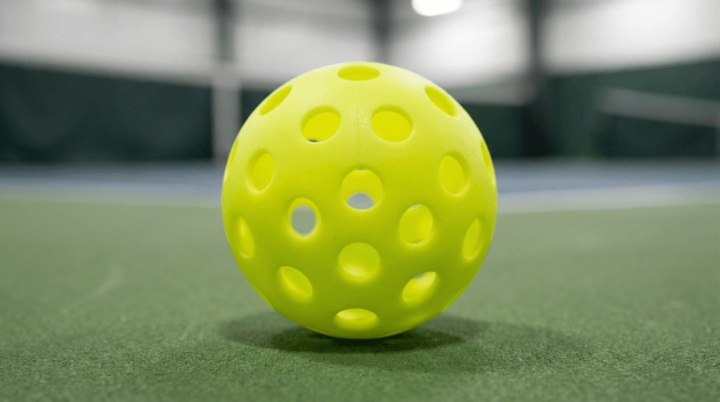 Different pickleball ball types including indoor and outdoor models on a court.