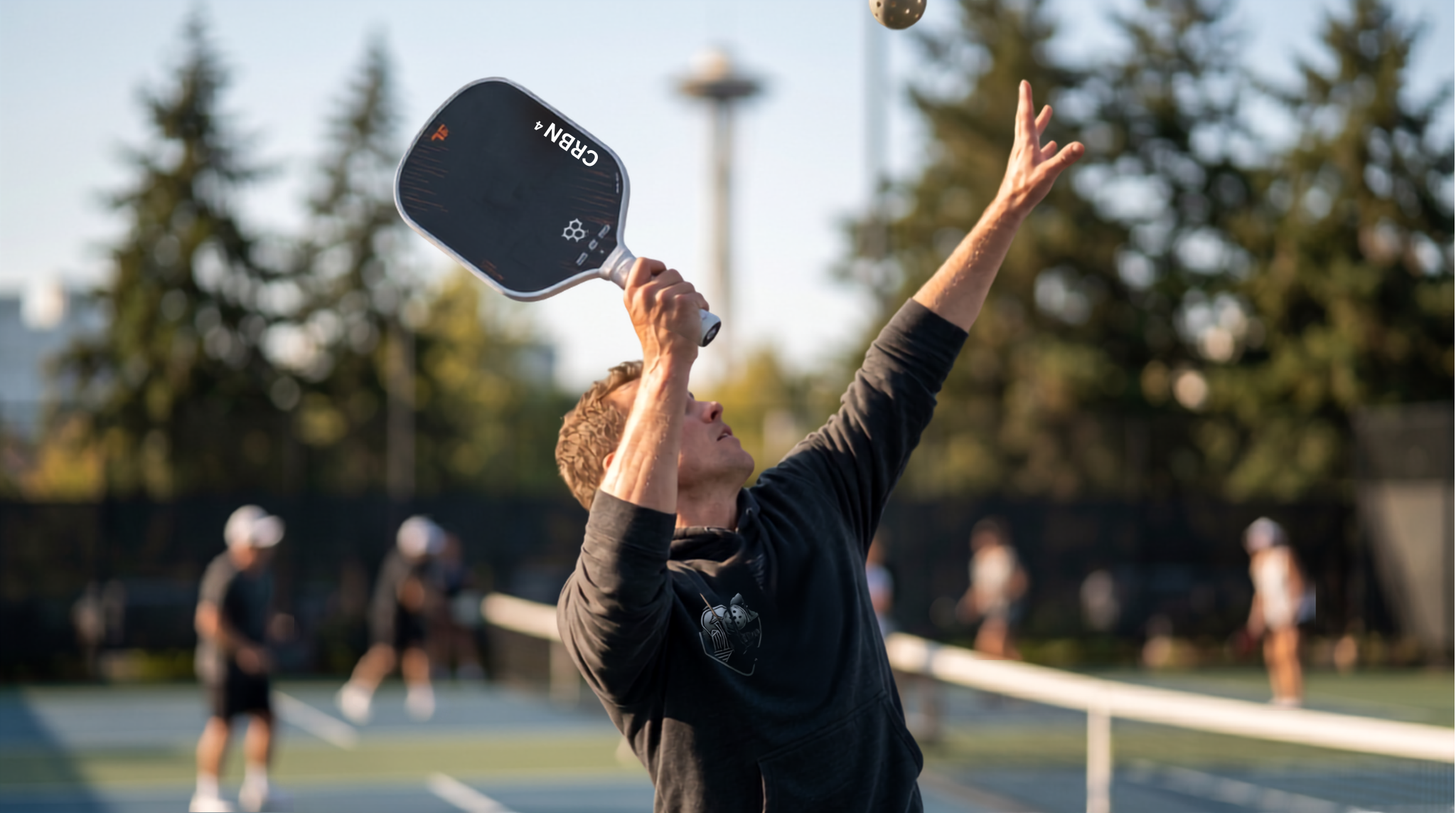 “hands holding a pickleball paddle performing a pickleball overhead shot drill on an outdoor court”